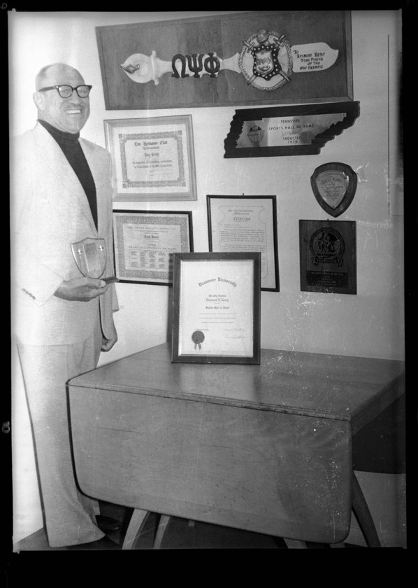 Raymond Kemp standing next to plaques awarded to Raymond Howard Kemp Duquesne University Sports