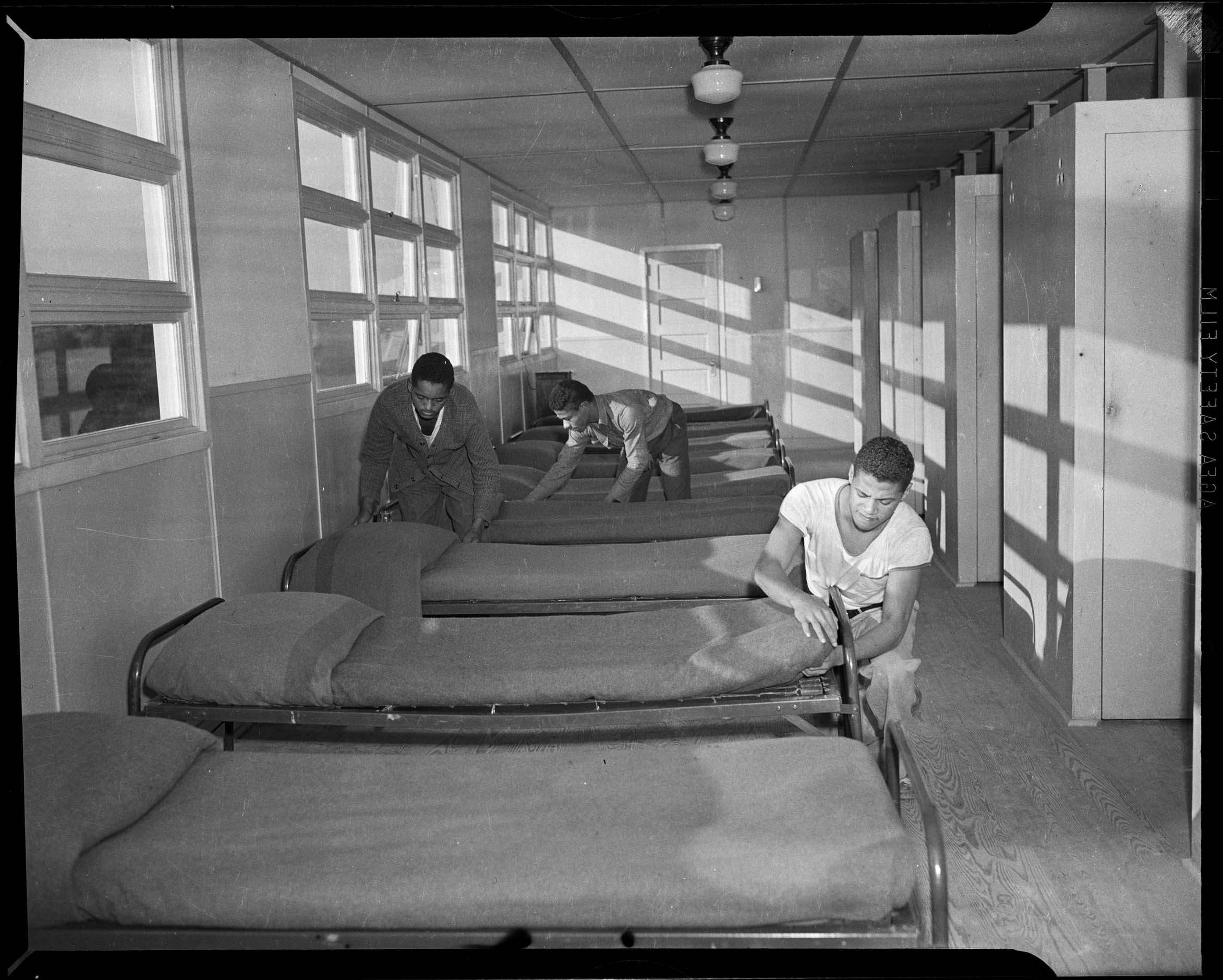 Three men making up cots in barracks CMOA Collection