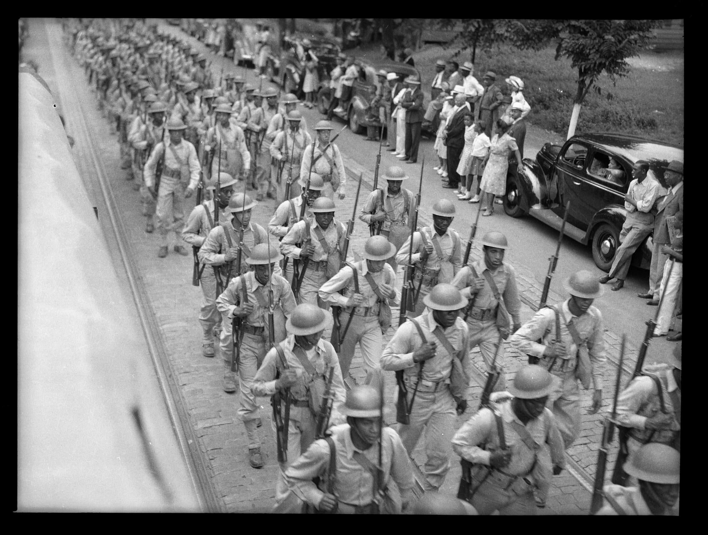 Soldiers with rifles, possibly from the garrison at Fort Indiantown Gap, parading down city