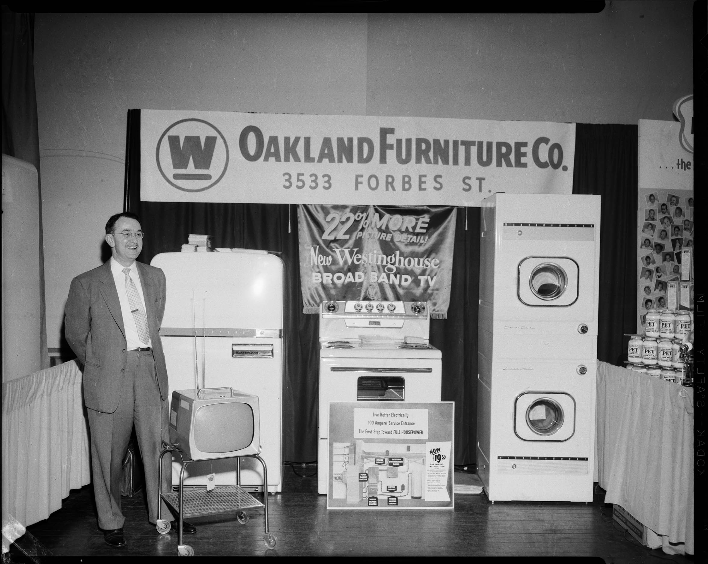 M.J. Bodek standing in Oakland Furniture Company booth in Syria Mosque for the 1957 Pittsburgh