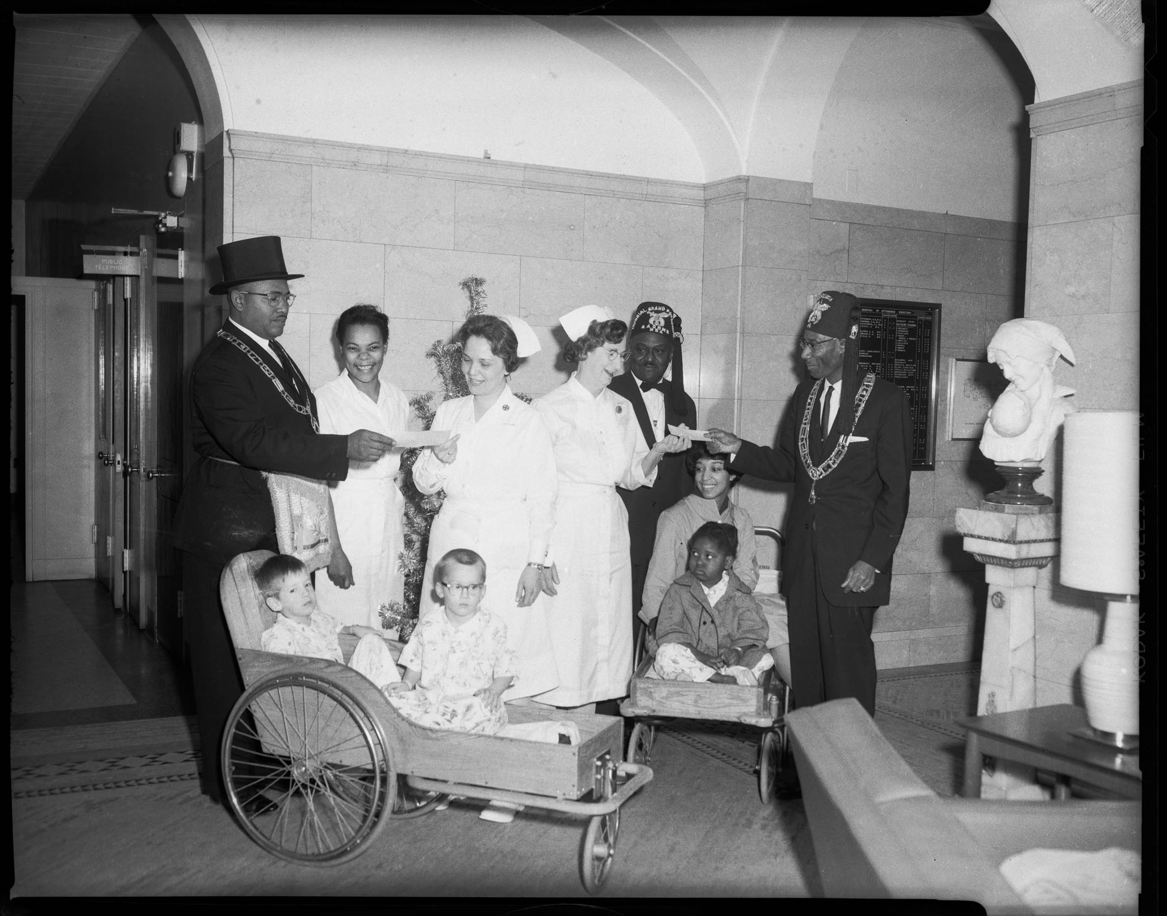 Group portrait of Shriners presenting donations to group of nurses