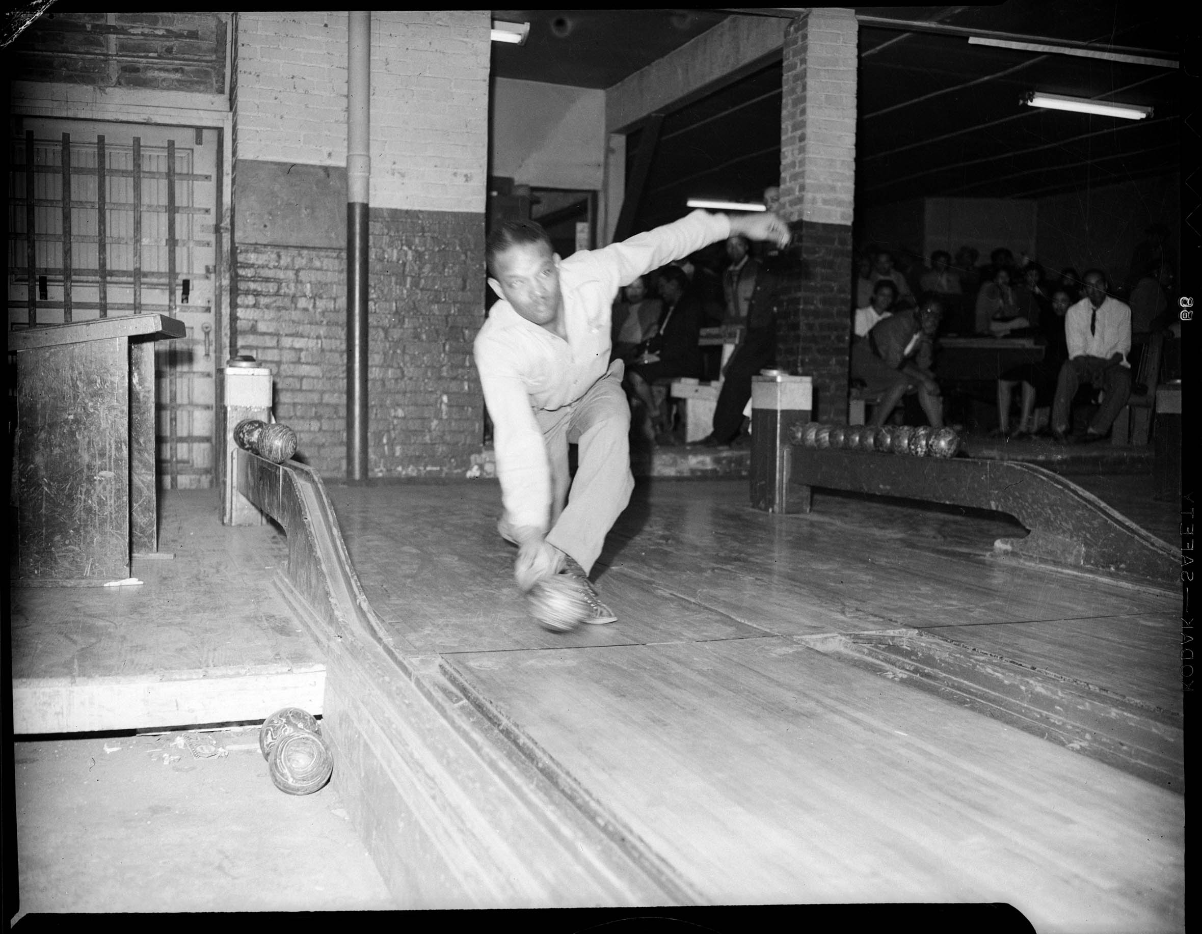 Man Wearing Light Colored Shirt Bowling In Lane At Bowling Alley