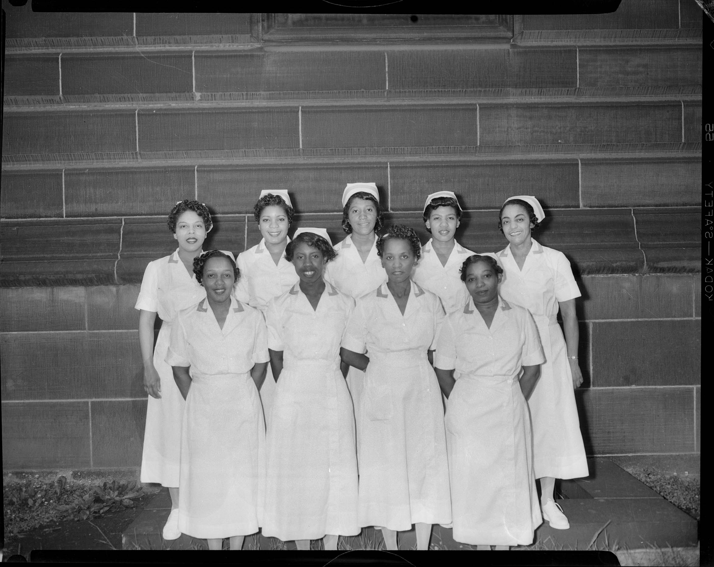 Group portrait of nine women wearing nursing uniforms, including one