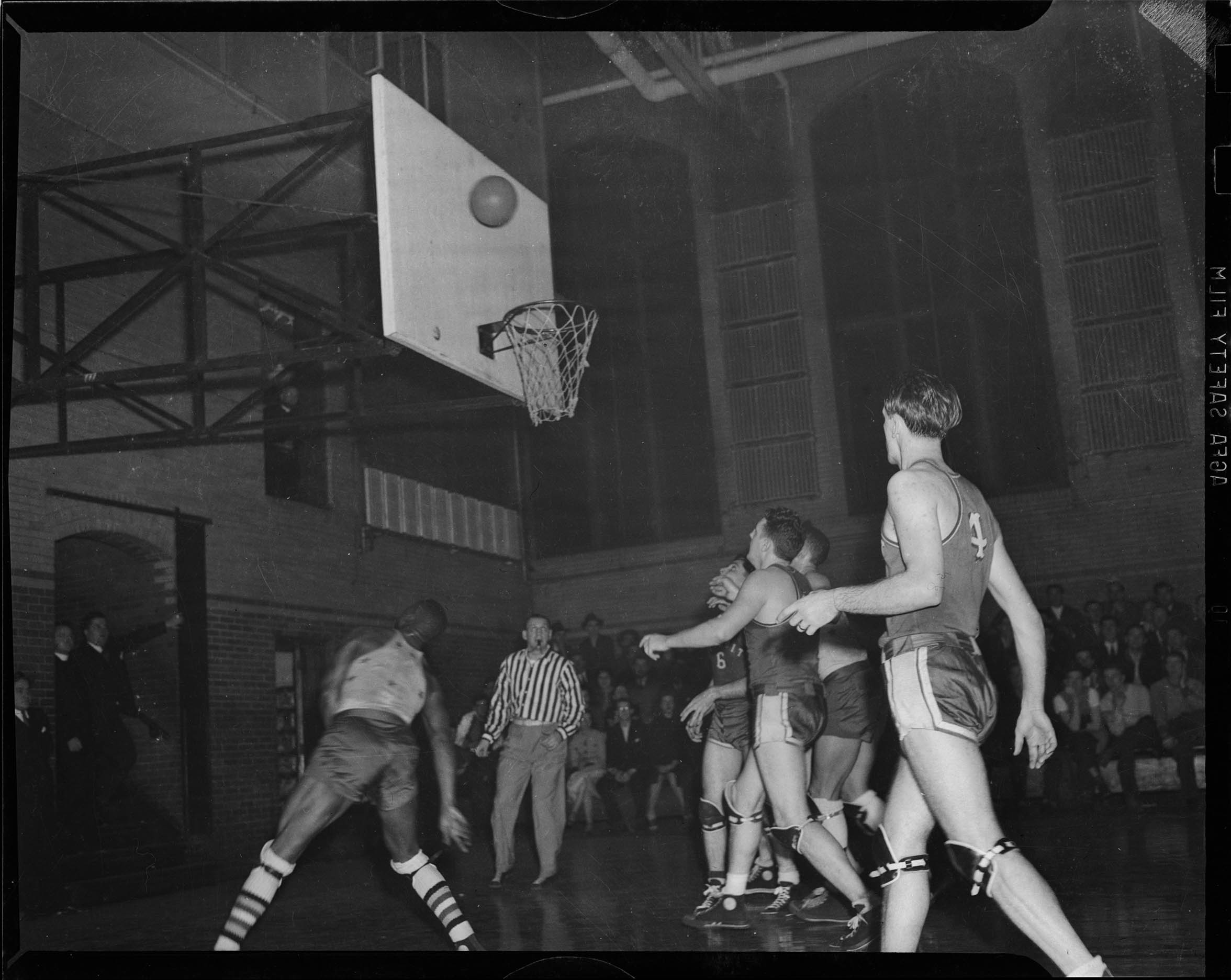 Five young men wearing dark basketball shorts and tank top, dark